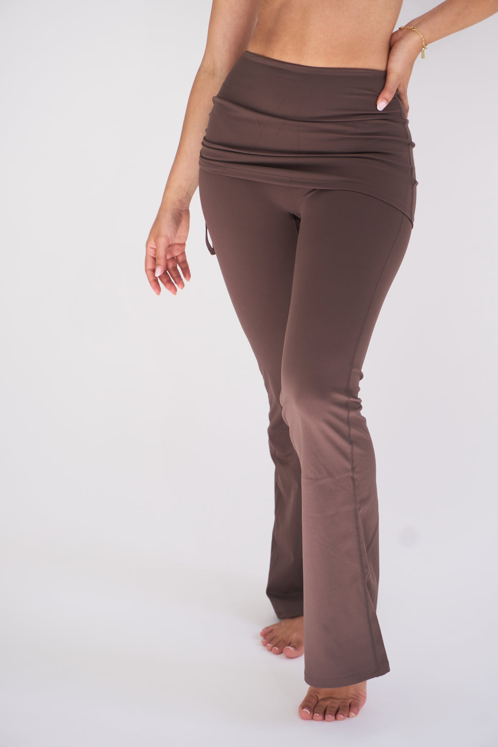 A model wearing cocoa high-waisted flared leggings, shown from the waist down against a plain white studio background.
